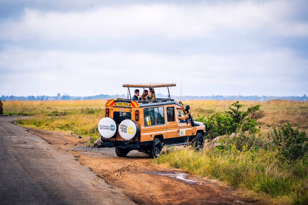 Une Jeep de safari avec des passagers qui observent la savane à travers le toit de la voiture.